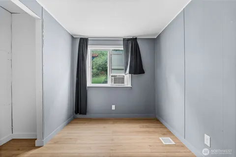 a view of an empty room with wooden floor and a window