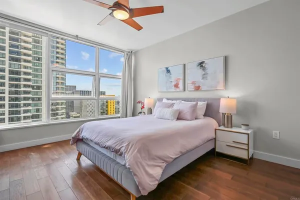 a bedroom with a bed painting on wall and a large window