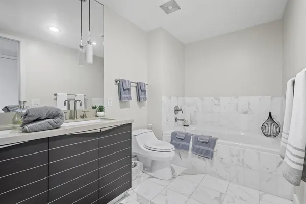 a spacious bathroom with a granite countertop toilet a sink and mirror