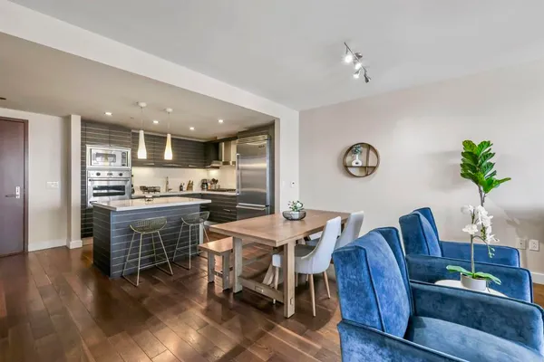 a living room with stainless steel appliances kitchen island granite countertop furniture wooden floor and a kitchen view