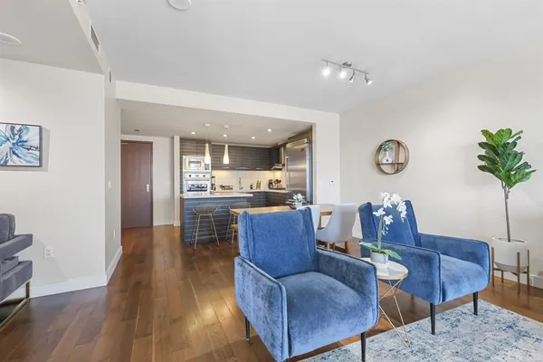 a living room with furniture and a dining table with wooden floor