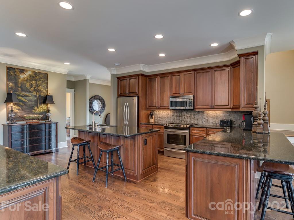 995 Deep Gap Farm Road East Mill Spring, NC 28756 - Photo 6 of 47 a kitchen with stainless steel appliances granite countertop a stove top oven a sink dishwasher a dining table and chairs with wooden floor