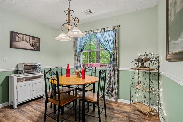 a dining room with wooden floor a chandelier a wooden table and chairs