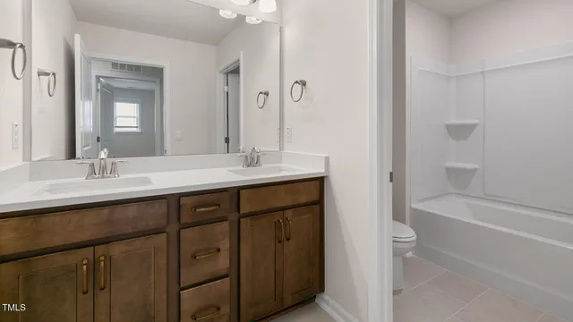 a bathroom with a double vanity sink a mirror and a bathtub
