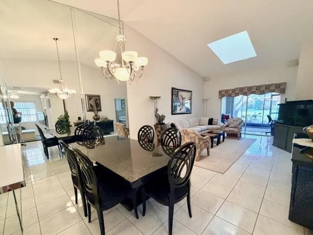 a view of a dining room and livingroom with furniture a rug a potted plant and a chandelier