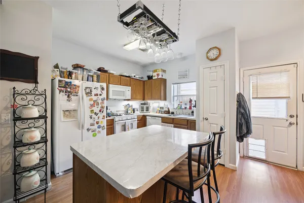 a kitchen with stainless steel appliances kitchen island granite countertop a table chairs and a refrigerator