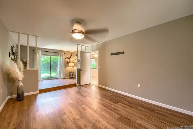 a view of an empty room with a window and wooden floor