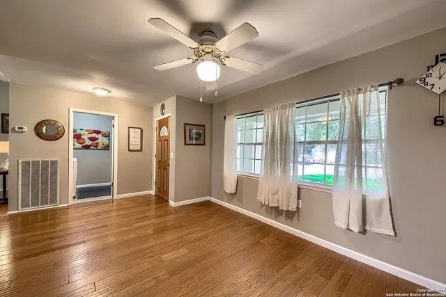 a view of an empty room with wooden floor and a window