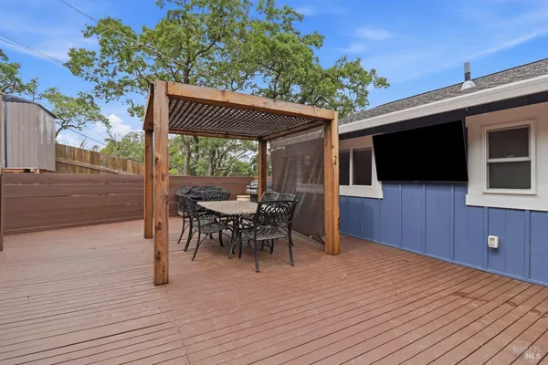 a view of a patio with table and chairs a barbeque with wooden floor and fence