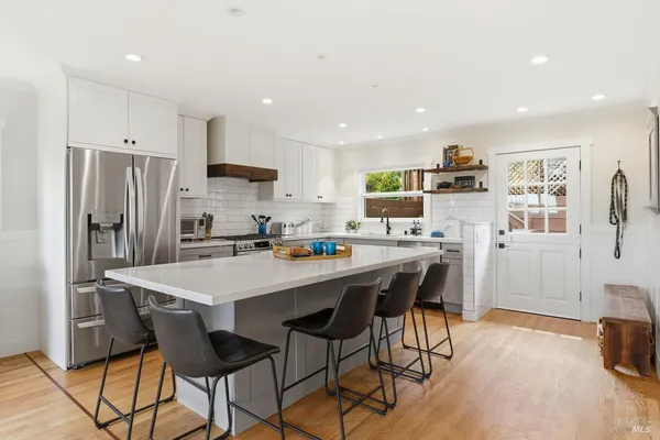 a kitchen with stainless steel appliances a refrigerator a stove a sink dishwasher and a dining table with wooden floor