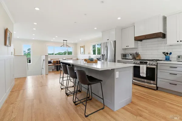 a kitchen with stainless steel appliances a dining table chairs stove refrigerator and cabinets