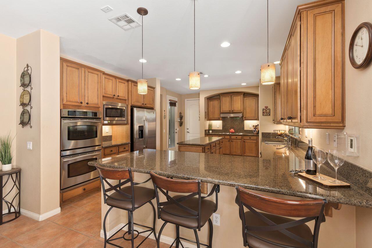 80591 Tangelo Court Indio, CA 92201 - Photo 6 of 30 a kitchen with kitchen island a stove a sink and a refrigerator with wooden floor
