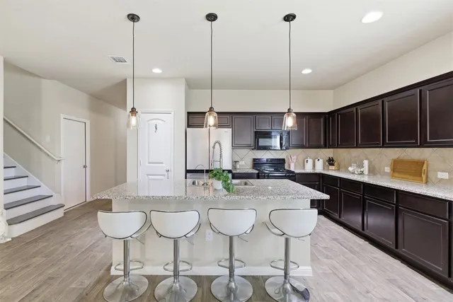 a kitchen with stainless steel appliances kitchen island granite countertop a dining table chairs and sink