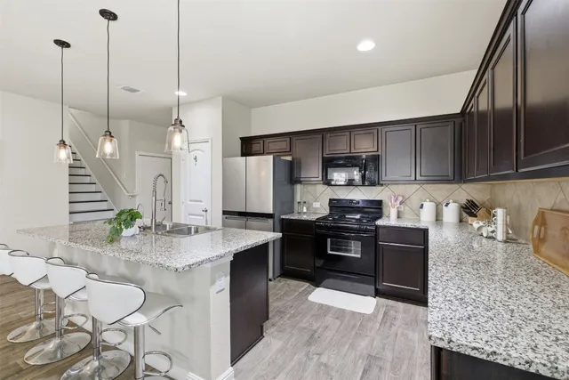 a kitchen with stainless steel appliances kitchen island granite countertop a sink a stove and a wooden floors