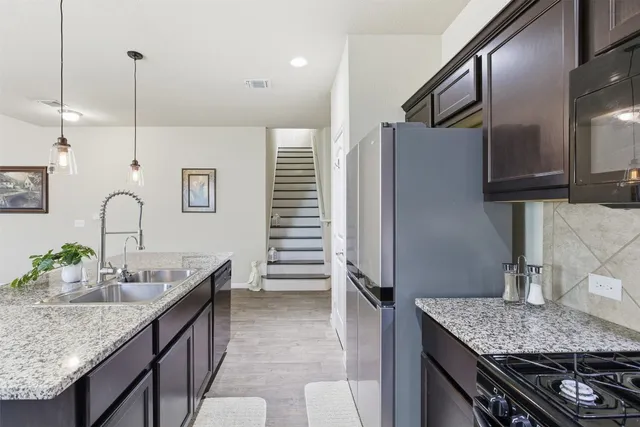 a kitchen with stainless steel appliances granite countertop a sink refrigerator and cabinets
