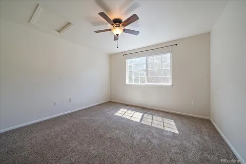 an empty room with windows and ceiling fan