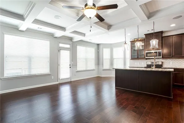 a kitchen with stainless steel appliances granite countertop a refrigerator a sink dishwasher a stove and white countertops with wooden floor