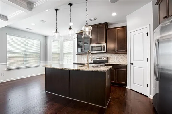 a kitchen with stainless steel appliances granite countertop a refrigerator a sink dishwasher a stove and white cabinets with wooden floor