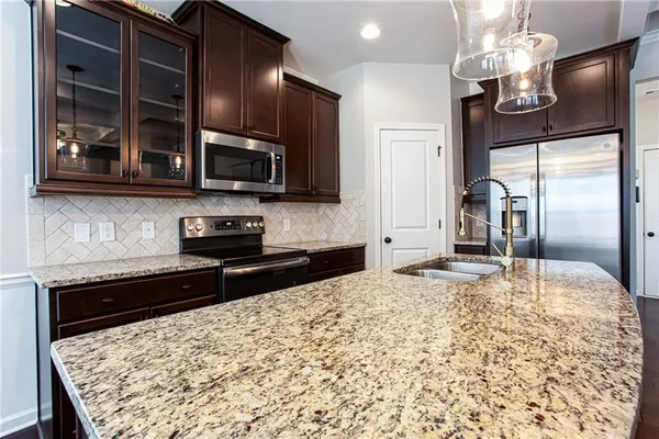 a kitchen with kitchen island granite countertop stainless steel appliances and stove top oven