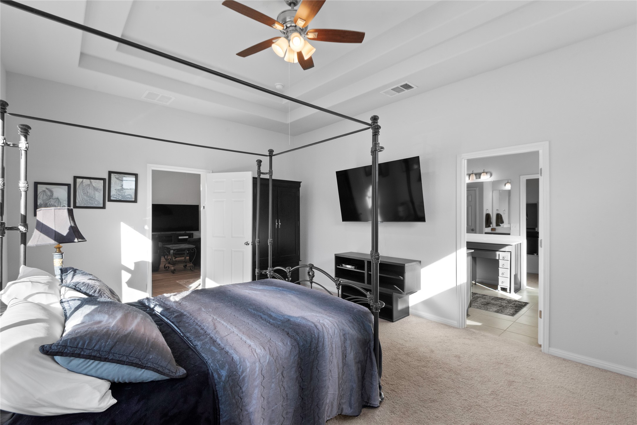 932 Medina Way Leander, TX 78641 - Photo 11 of 28 Bedroom featuring a raised ceiling, ceiling fan, light carpet, and connected bathroom