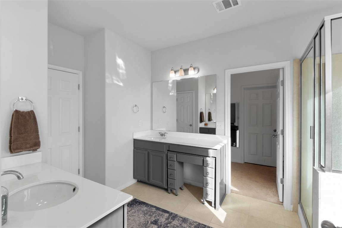 932 Medina Way Leander, TX 78641 - Photo 13 of 28 Full bathroom with two vanities, a shower stall, and light tile patterned floors