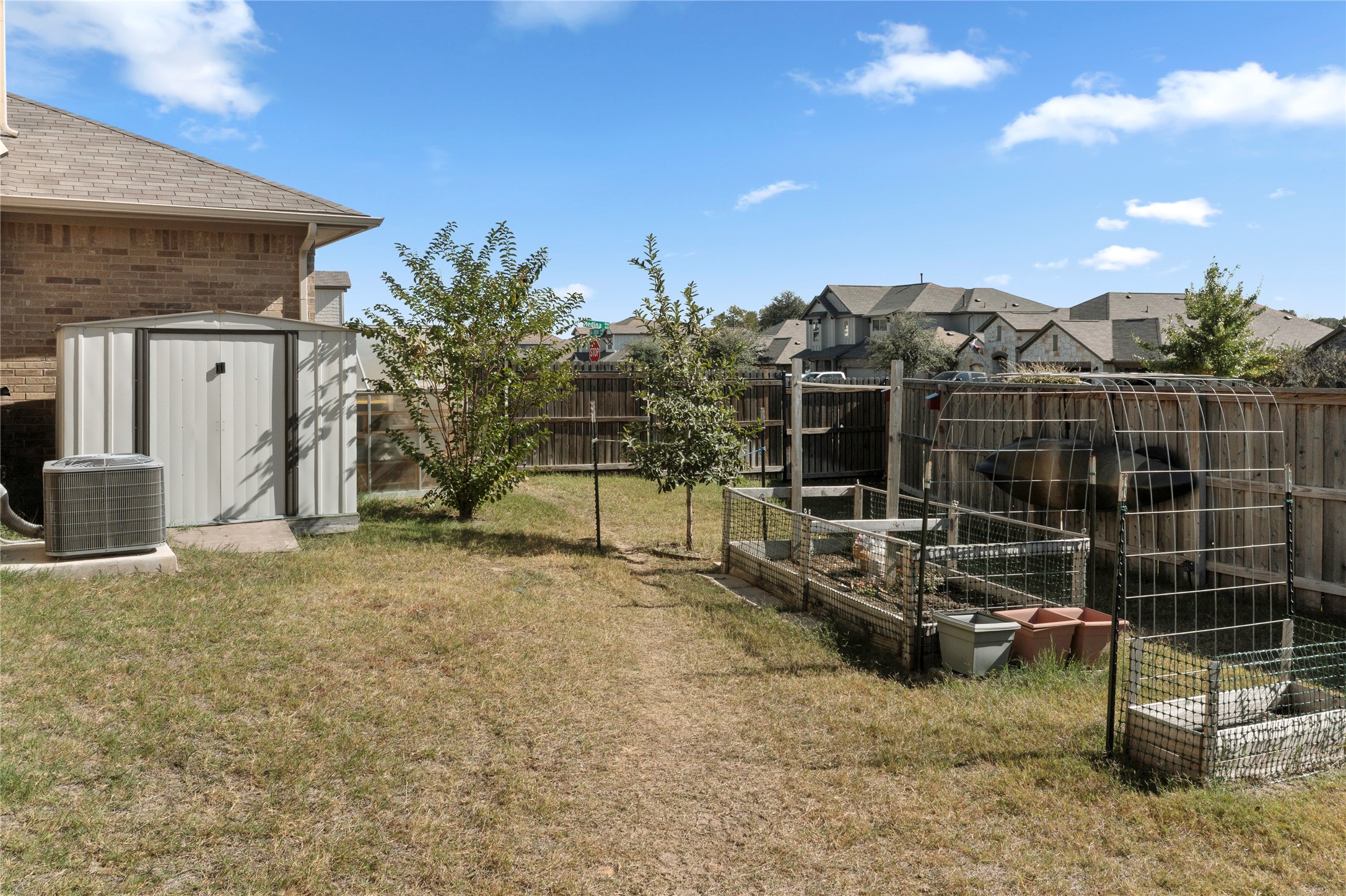 932 Medina Way Leander, TX 78641 - Photo 21 of 28 Fenced backyard with a garden, a shed, and a residential view