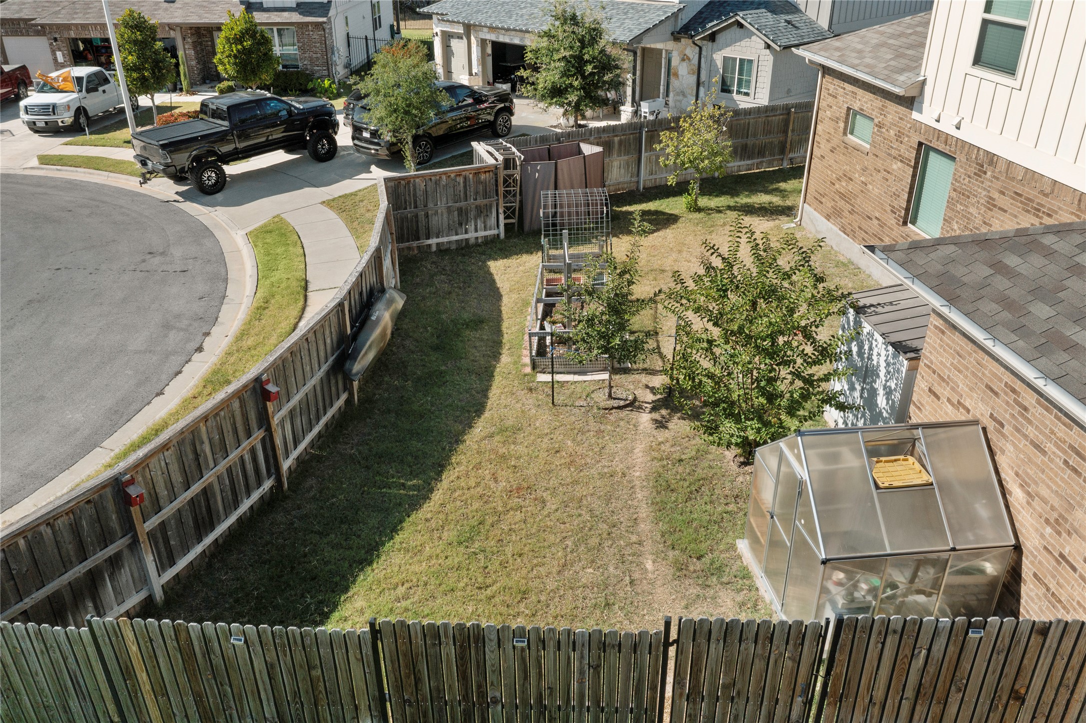 932 Medina Way Leander, TX 78641 - Photo 23 of 28 Fenced backyard with a residential view, a greenhouse, and a garden