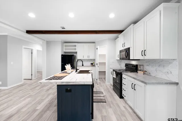 a open kitchen with kitchen island a sink stove and white cabinets