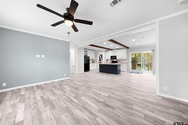 a view of empty room with wooden floor and ceiling fan