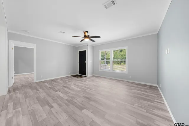 a view of an empty room with a window and wooden floor