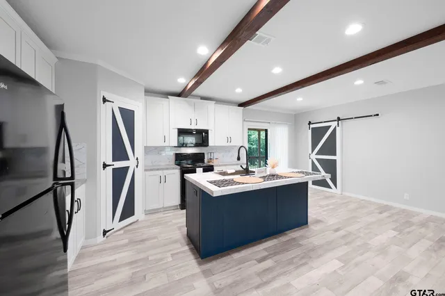 a kitchen with kitchen island stainless steel appliances a sink stove refrigerator and cabinets