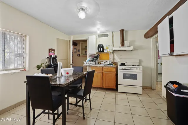 a kitchen with a stove a table and chairs in it