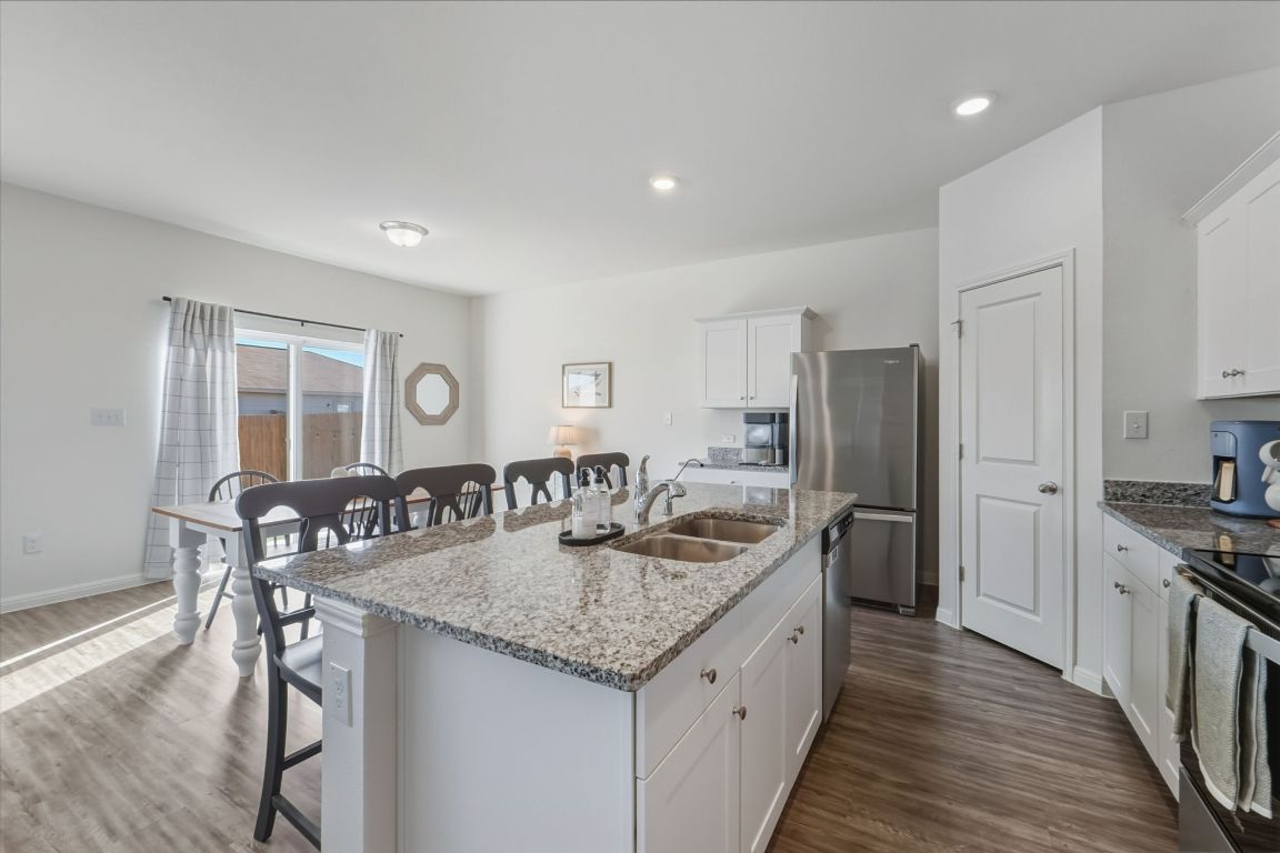 201 Wonderful Life Way Jarrell, TX 76537 - Photo 8 of 39 Kitchen featuring a breakfast bar area, white 36 inch cabinetry, granite counters, a kitchen island with sink, and dark wood finished floors