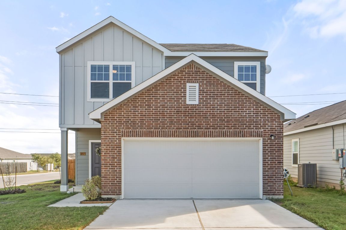 201 Wonderful Life Way Jarrell, TX 76537 - Photo 5 of 39 View of front of home with board and batten siding, brick siding, a front yard, and driveway