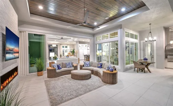 a living room with furniture a flat screen tv and floor to ceiling window