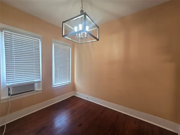 an empty room with wooden floor chandelier and window