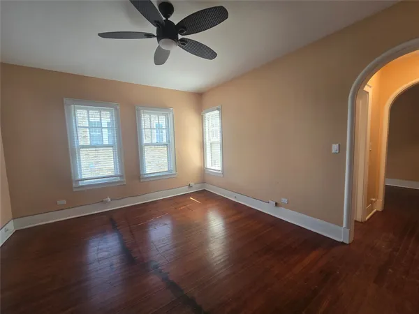 a view of empty room with wooden floor and fan