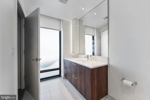 a spacious bathroom with a double vanity sink toilet mirror and bathtub