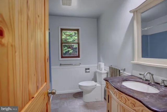 a bathroom with a granite countertop sink a toilet and a mirror