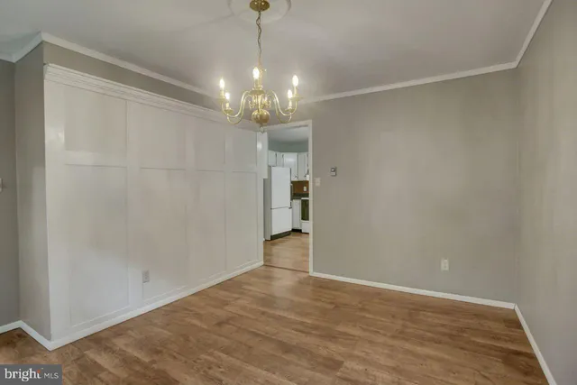 a view of an empty room with wooden floor and chandelier