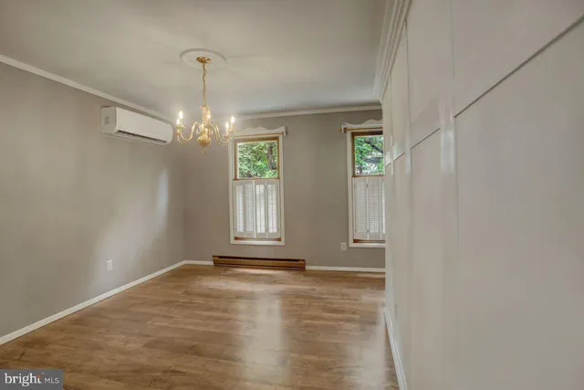a view of an empty room with window and chandelier fan