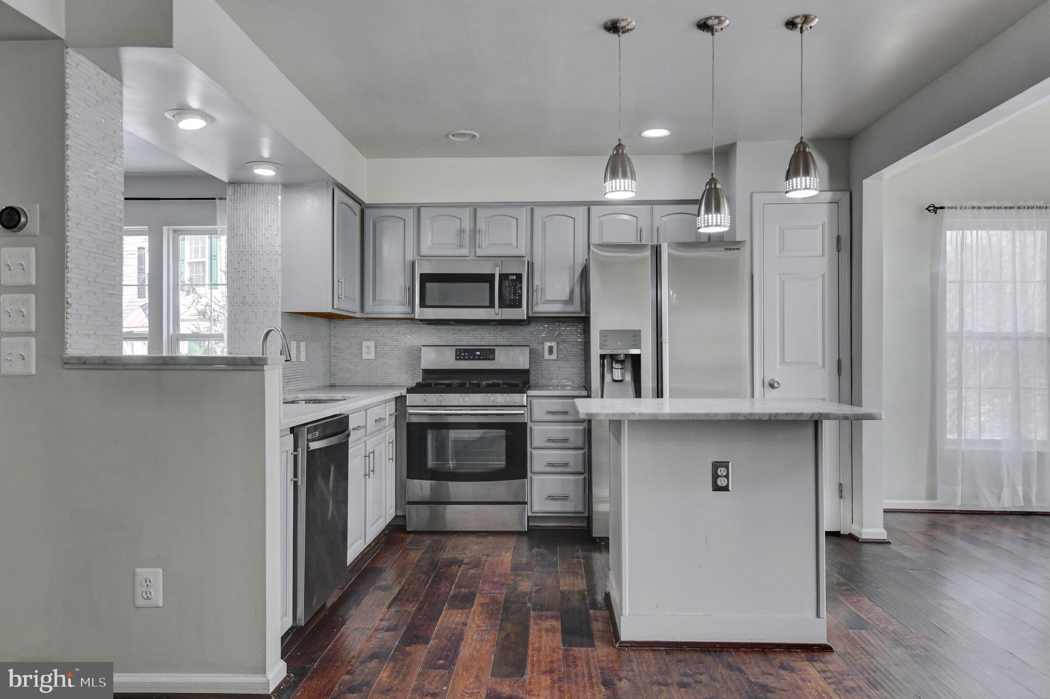 4013 Mammoth Cave Loop Dumfries, VA 22025 - Photo 11 of 38 a kitchen with kitchen island granite countertop a stove a sink and a microwave