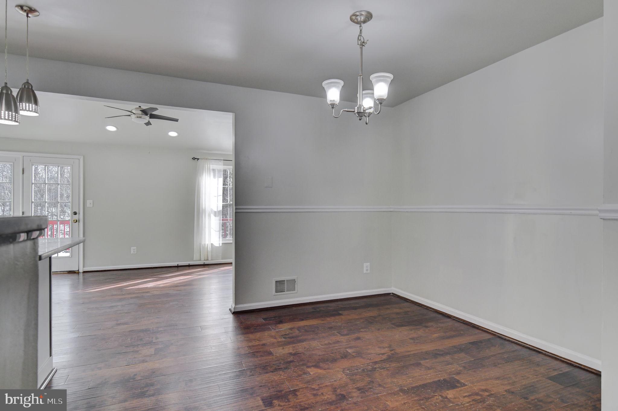 4013 Mammoth Cave Loop Dumfries, VA 22025 - Photo 9 of 38 an empty room with wooden floor and chandelier