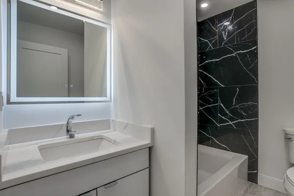 a bathroom with a sink and mirror with bathtub