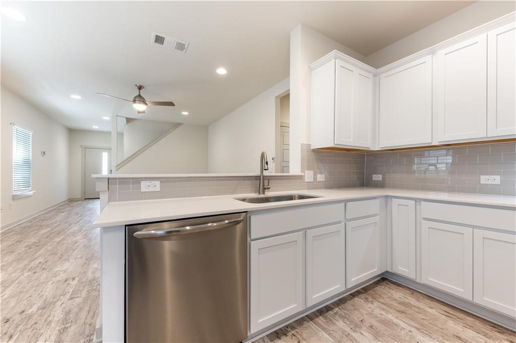 8304 Mimi Lane Austin, TX 78724 - Photo 5 of 32 a kitchen with a sink dishwasher and white cabinets with wooden floor