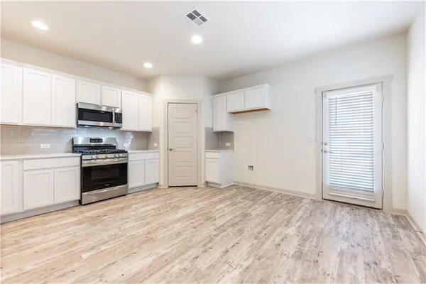 a kitchen with stainless steel appliances granite countertop a stove top oven a sink and a refrigerator