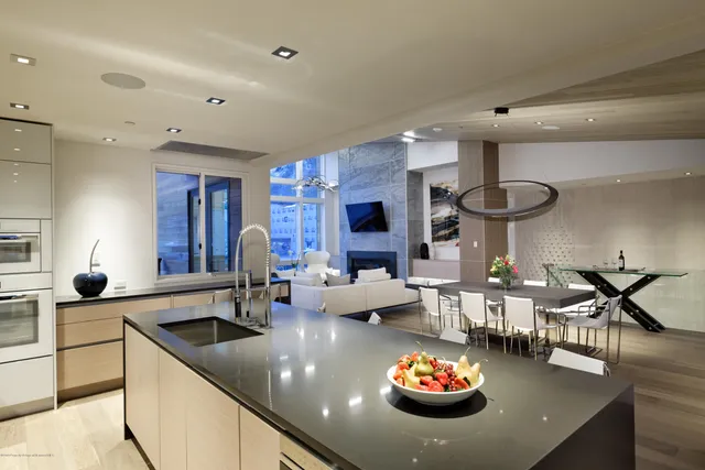 a kitchen with stainless steel appliances kitchen island granite countertop a table chairs sink and cabinets