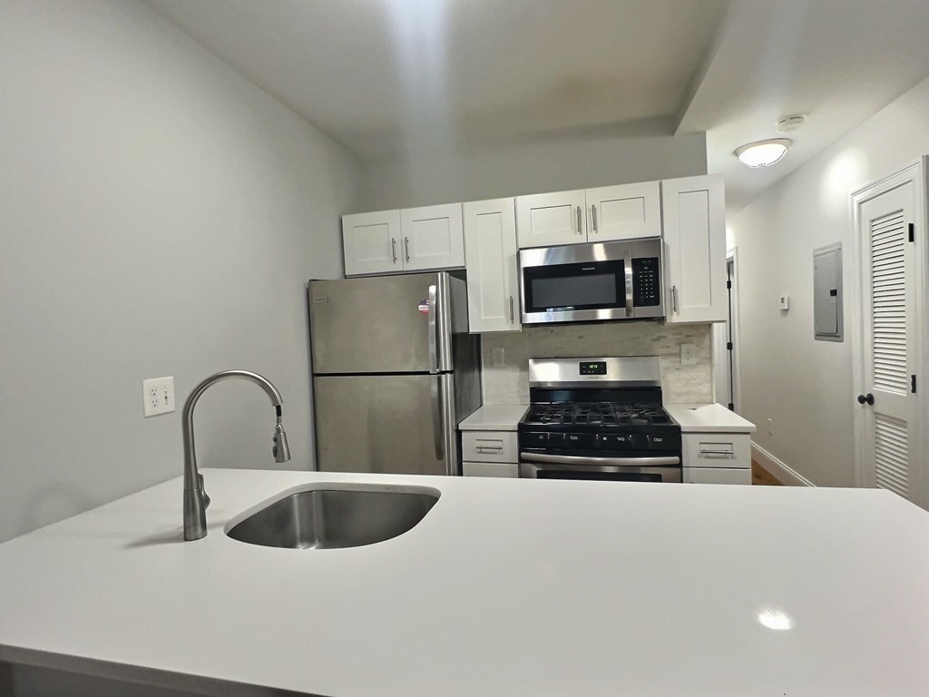 255 Paris Street, Unit 1 Boston, MA 02128 - Photo 5 of 15 a kitchen with sink a refrigerator and a stove top oven with wooden floor