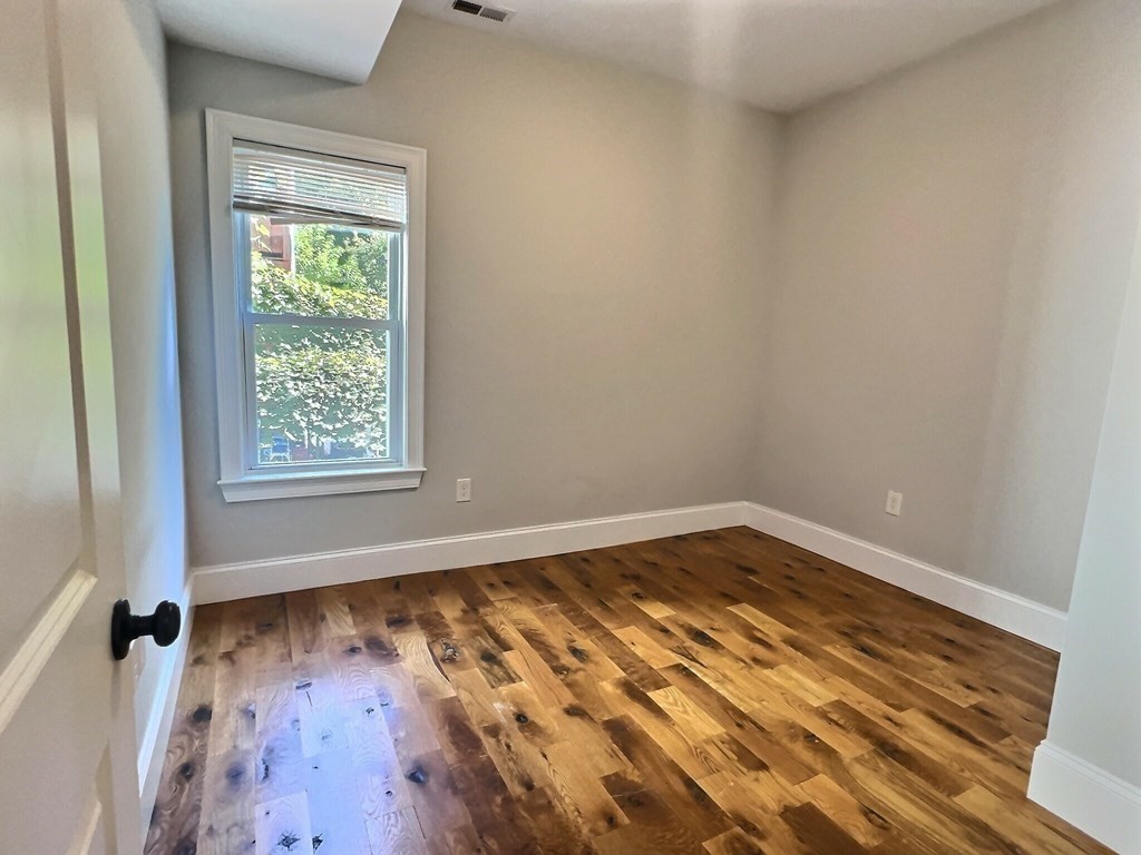 255 Paris Street, Unit 1 Boston, MA 02128 - Photo 9 of 15 an empty room with wooden floor and windows
