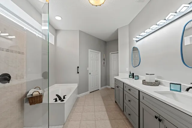 a spacious bathroom with a double vanity sink a mirror a bathtub and shower